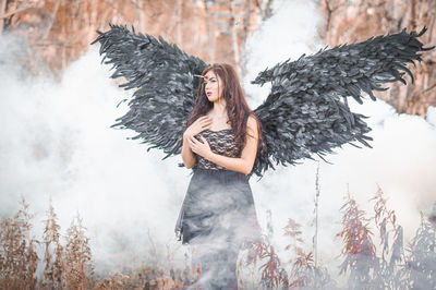Portrait of young woman standing against waterfall