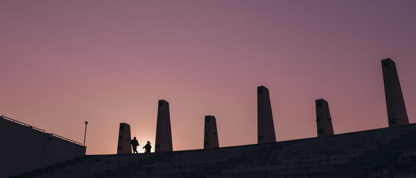 Low angle view of silhouette people against orange sky