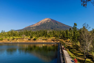 Scenic view of lake and mountains against clear blue sky