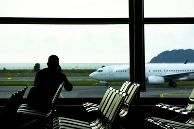 Rear view of man sitting in waiting room at airport