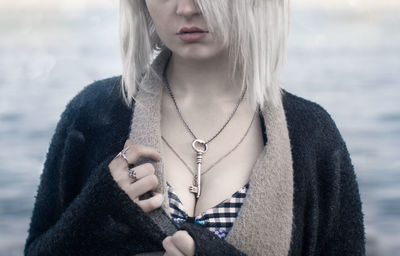 Midsection of beautiful young woman wearing chain with key pendant at beach