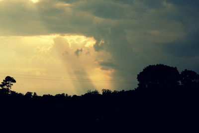 Silhouette of trees against cloudy sky