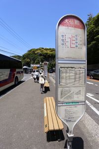 Information sign on road in city against sky