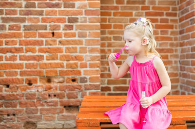 Portrait of girl standing against brick wall