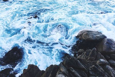 High angle view of waves splashing on rocks