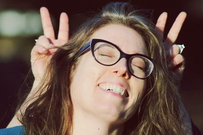 Close-up of happy woman with finger horns