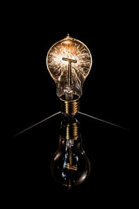 Close-up of illuminated light bulb against black background