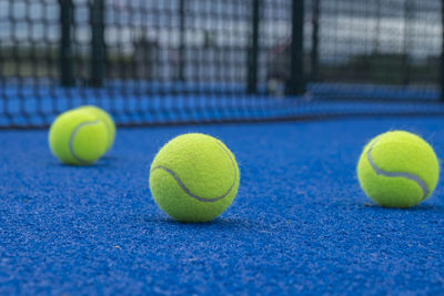 Selective focus, paddle tennis balls on a blue paddle tennis court