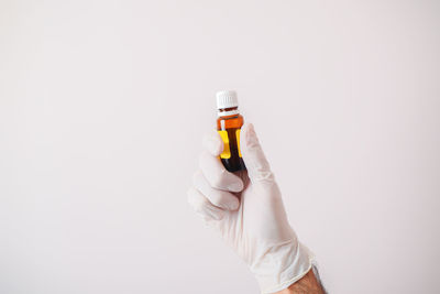 Midsection of person holding bottle against white background