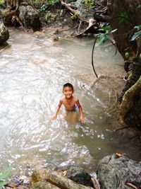 High angle portrait of smiling girl on rock