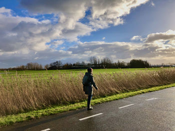 Rear view of man walking on road against sky