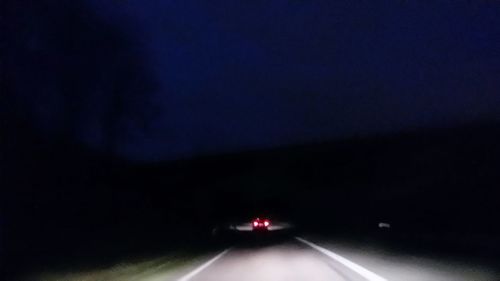 Car on illuminated road against sky at night