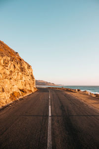 Road by sea against clear sky