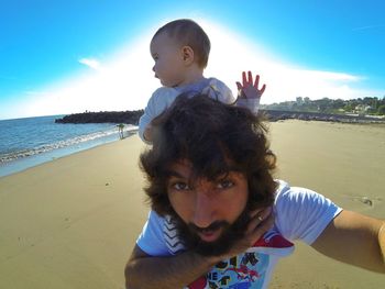 Portrait of happy friends on beach against sky