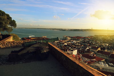 High angle view of cityscape by sea against sky during sunset