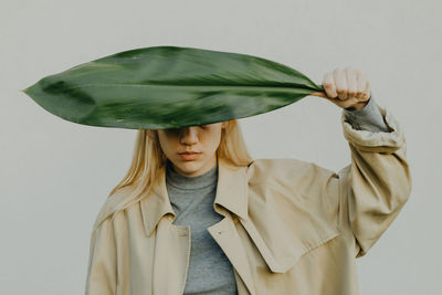 A portrait of a young woman holding a plant leaf