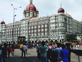 Group of people in front of building called taj mahal palace and tower