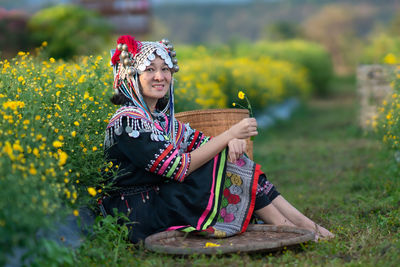 Full length of woman holding yellow flower in field