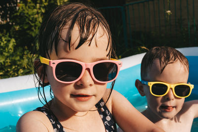 Portrait of happy children in sunglasses in swimming pool on summer hot day