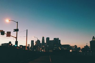 Illuminated city against clear sky during sunset