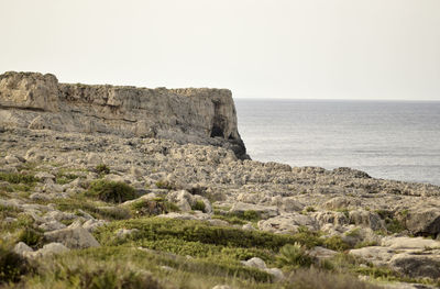 Scenic view of rocks on sea against clear sky