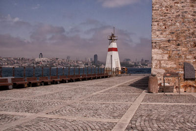 Lighthouse by sea against sky in city