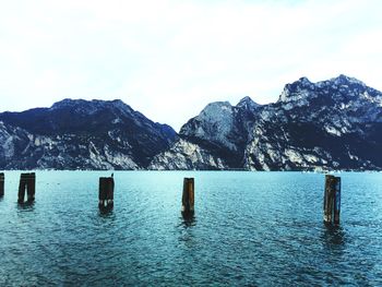 Wooden posts in lake against mountains