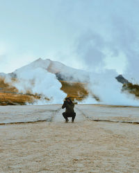 Rear view of man standing on mountain against sky