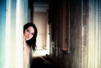Portrait of woman standing behind door