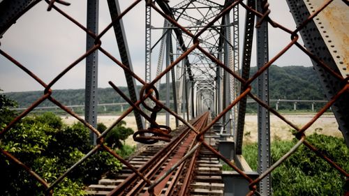 Railway bridge seen through chainlink fence