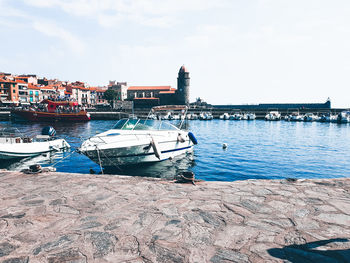 Boats moored at harbor in city against sky