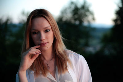 Close-up portrait of beautiful woman standing against trees