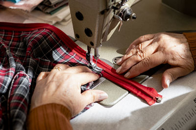 Close up of senior dressmaker hands sewing a zipper.