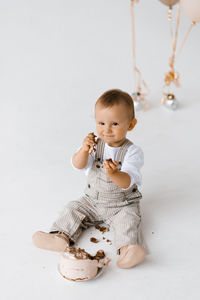 Portrait of cute baby boy playing with toy against white background