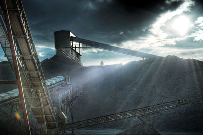 Suspension bridge in factory against sky