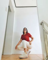 Low angle view of young woman sitting on escalator