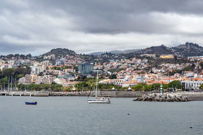 Scenic view of sea by townscape against sky