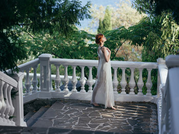 Woman standing by railing against trees