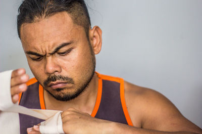 Close-up of man applying bandage against white background