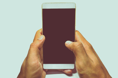 Close-up of hand holding smart phone against white background