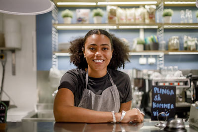 Portrait of smiling saleswoman at checkout counter in grocery store