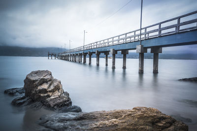 Bridge over calm sea against sky