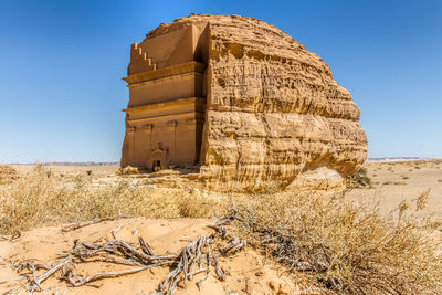 The unique castle of hegra at alula historical sites, scenic view of desert against clear blue sky.