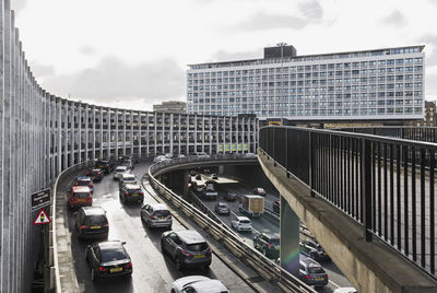 Vehicles on road in city against sky