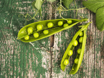 High angle view of green peas on weathered wooden table
