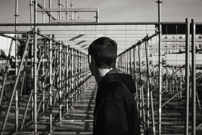 Man standing by railing against sky
