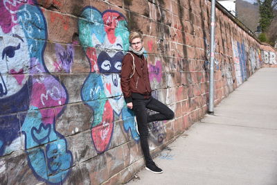 Portrait of man standing by graffiti on wall