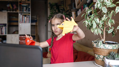 Cute girl holding origami at home