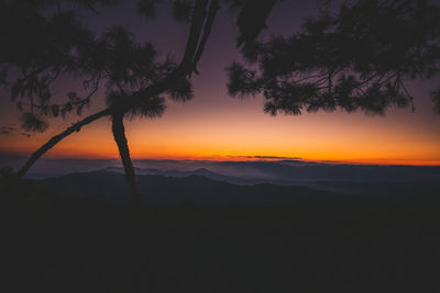 Scenic view of silhouette mountains against orange sky