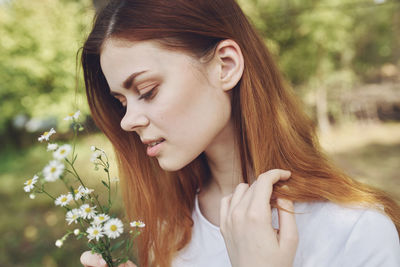 Close-up portrait of beautiful woman with red flower
